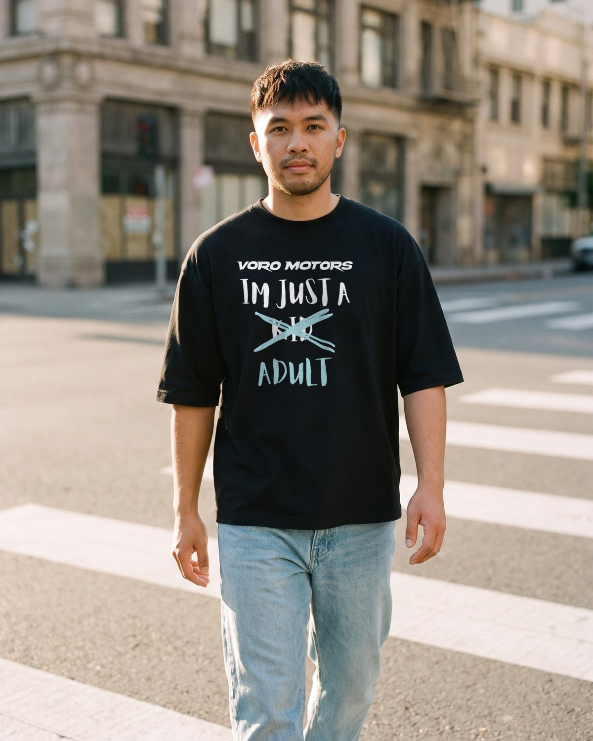 Man walking across a downtown LA crosswalk in the I'm Just a Kid Adult oversized tee