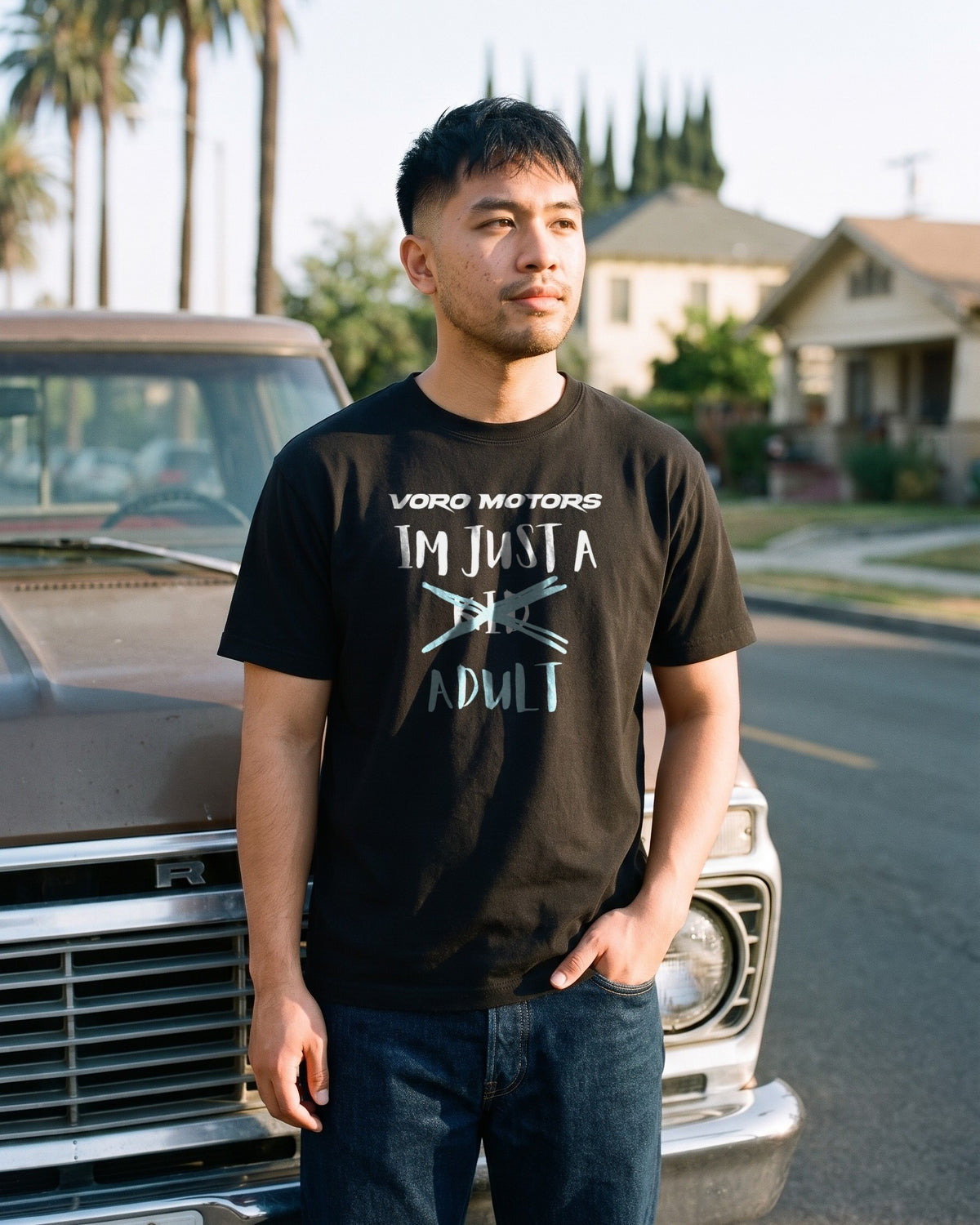 Man in the I'm Just a Kid Adult tee by a vintage pickup in Eagle Rock