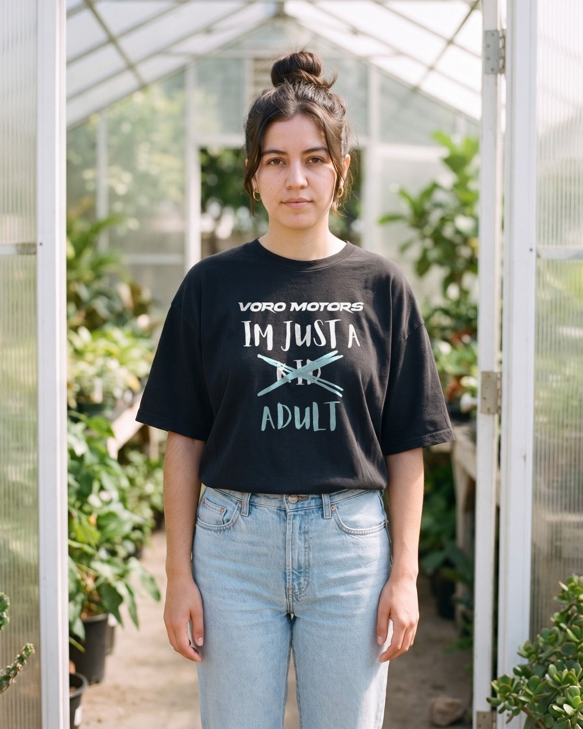 Woman in the I'm Just a Kid Adult tee in a Pasadena greenhouse