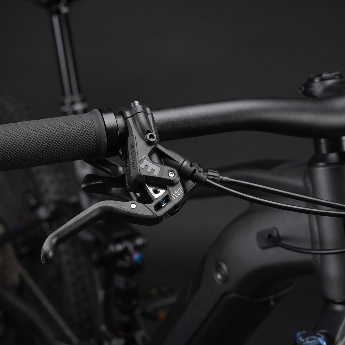 Magura MT5e hydraulic brake lever mounted on an e-bike handlebar, with the brake sensor wire routed along the bar