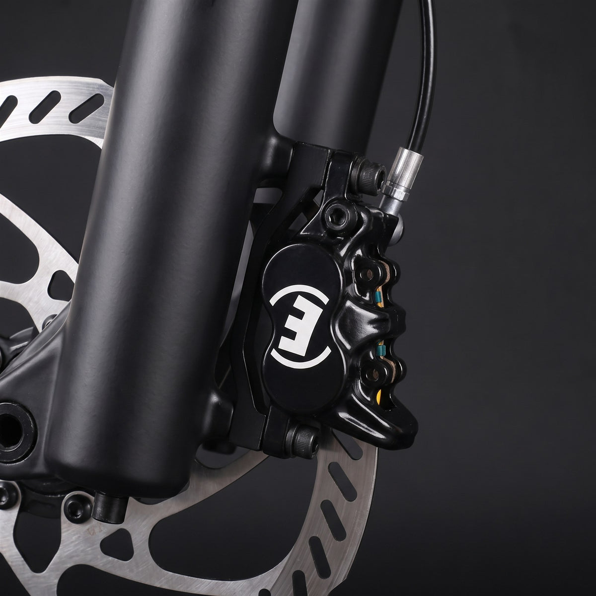Magura MT5e four-piston brake caliper bolted to a fork through a mounting bracket, on a disc rotor