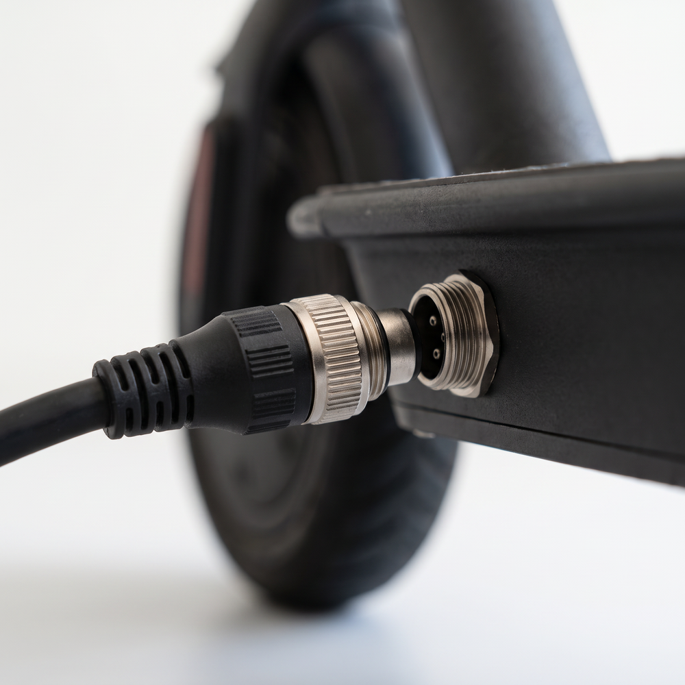 VM 1 charger connector being plugged into the charge port on the scooter deck