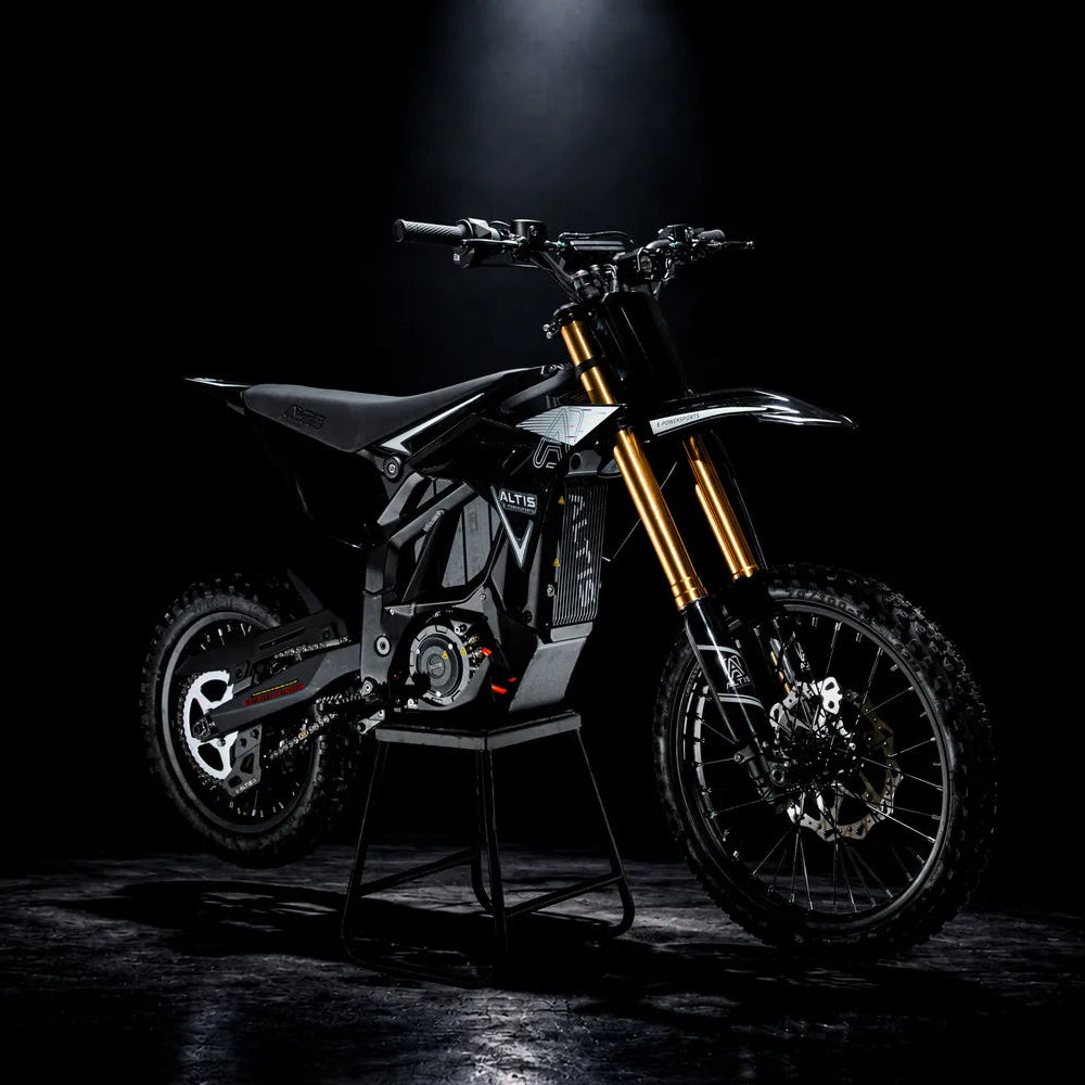 Black Altis Sigma electric dirt bike from the front three-quarter angle, on a stand under a spotlight