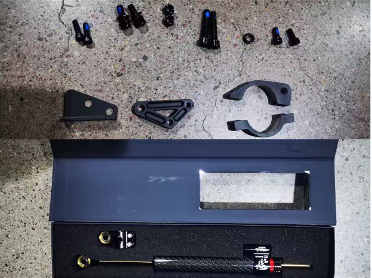 Everything in the Hooga Daytona steering damper kit laid out: damper, mounting brackets, bar clamp, bolts and nuts