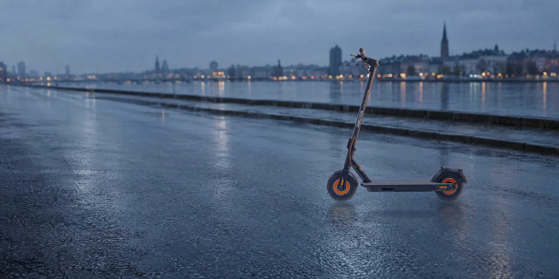 InMotion Climber folding electric scooter with orange wheels, standing on a wet city street at dawn