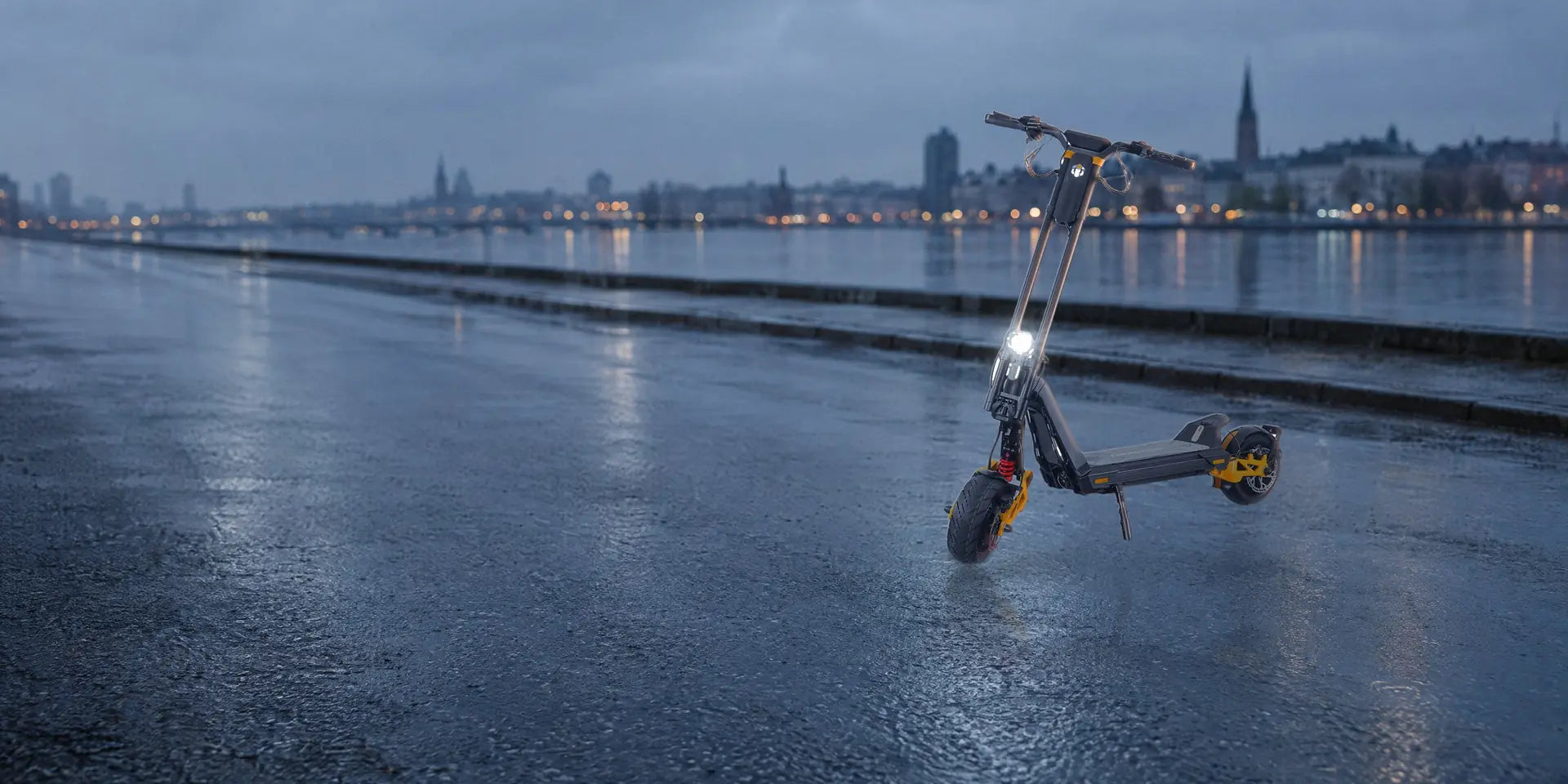InMotion RS Jet electric scooter with orange suspension arms, standing on a wet city street at dawn