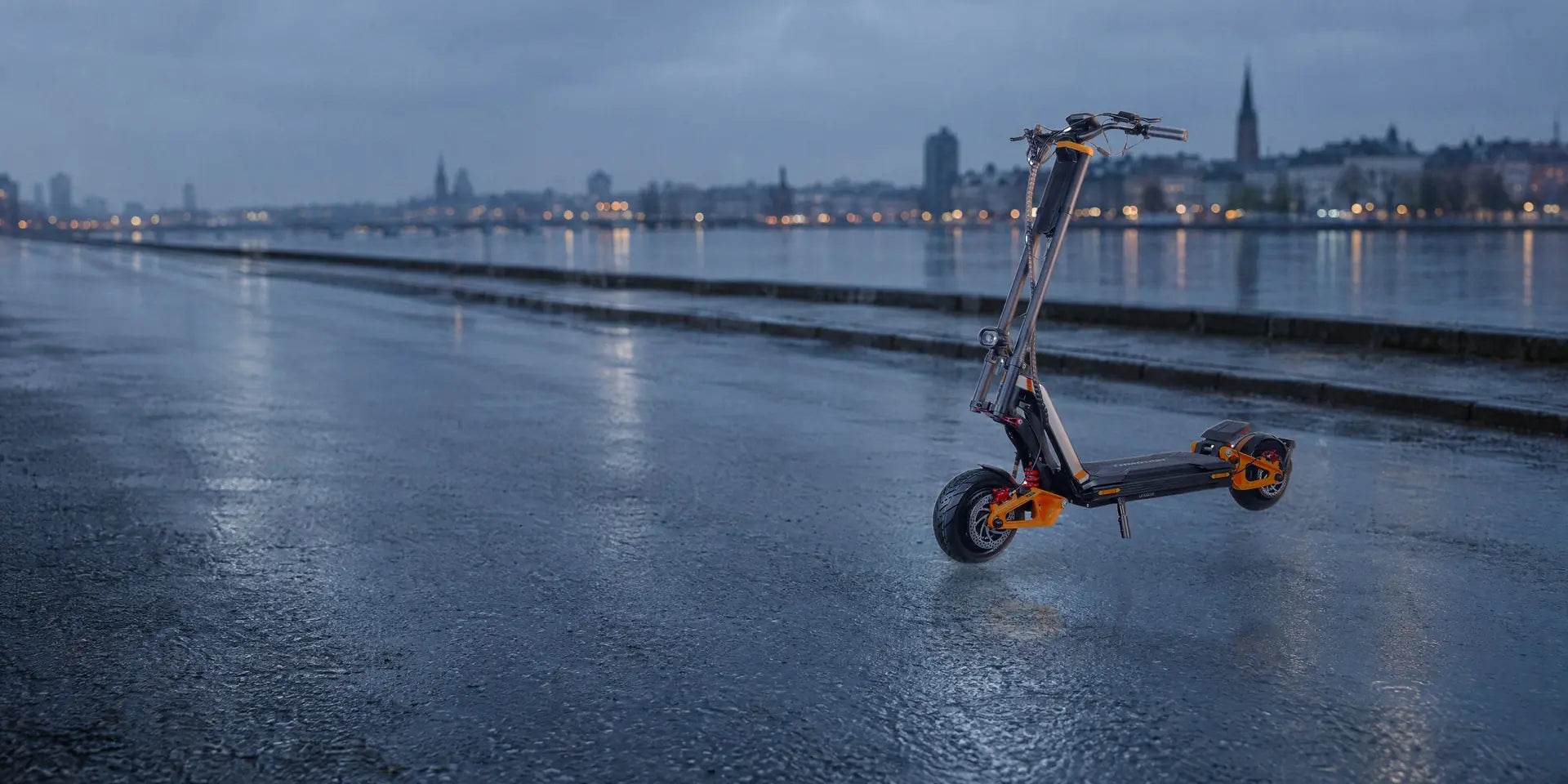 InMotion RS Lite electric scooter with orange suspension arms, standing on a wet city street at dawn